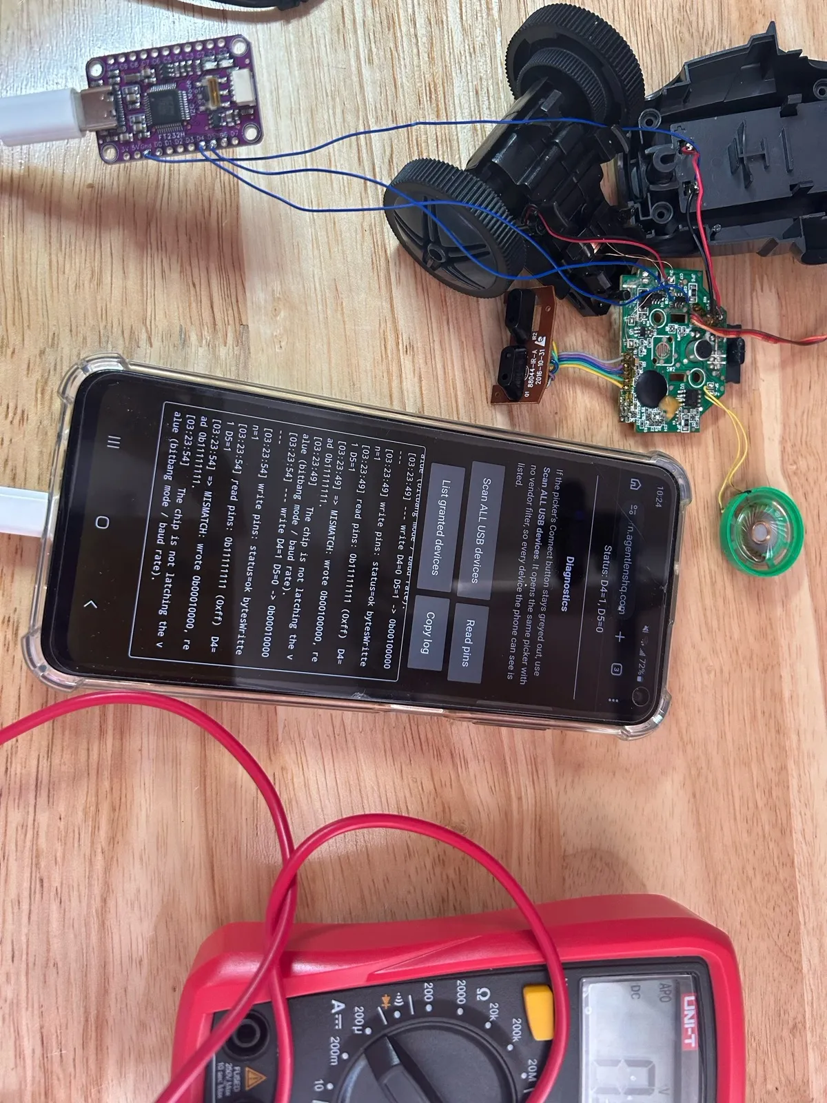 The debugging bench: the phone plugged into the FT232H, next to the opened robot and a multimeter